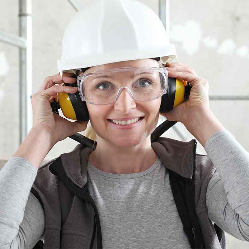 Worker in hardhat putting on hearing protection