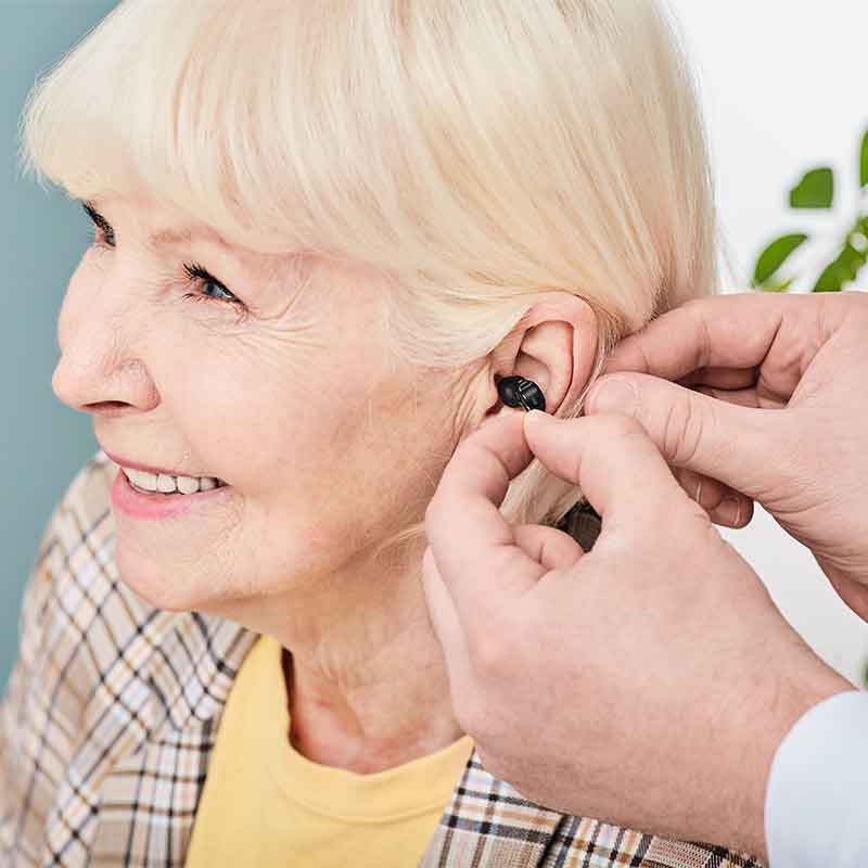A senior woman being fitted with a hearing aid